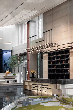 Cascading glass cylinder chandelier with staggered pendant drops above a reception lounge counter