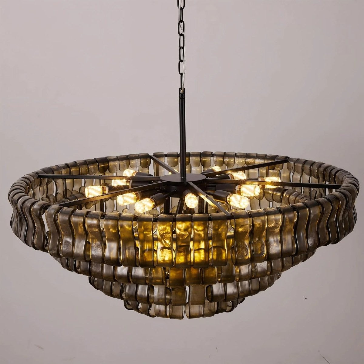 Angled underside view revealing the radial metal frame and warm glowing bulbs inside the wavy smoked glass tiers